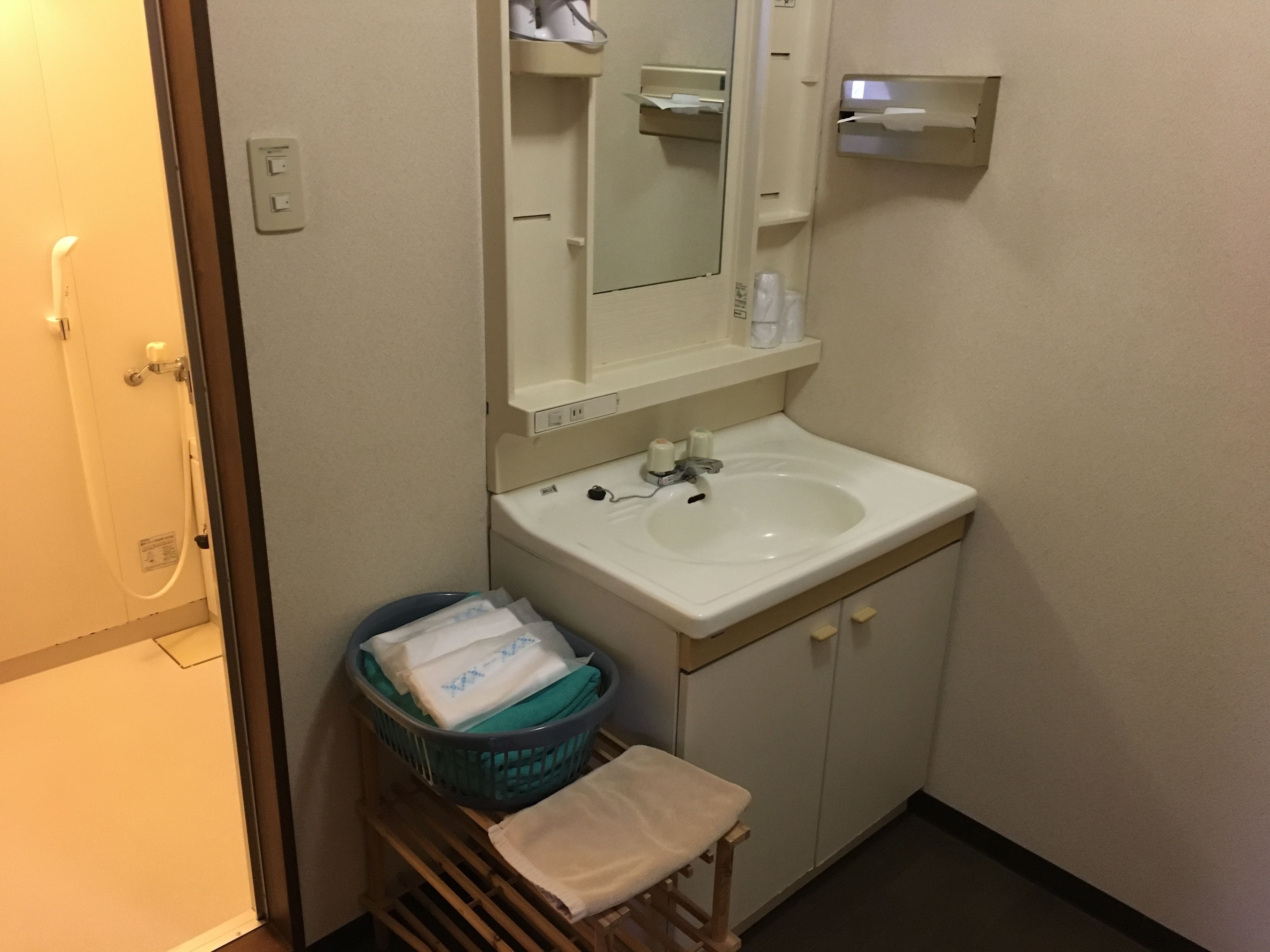 Un baño con lavamanos, espejo y toallero.