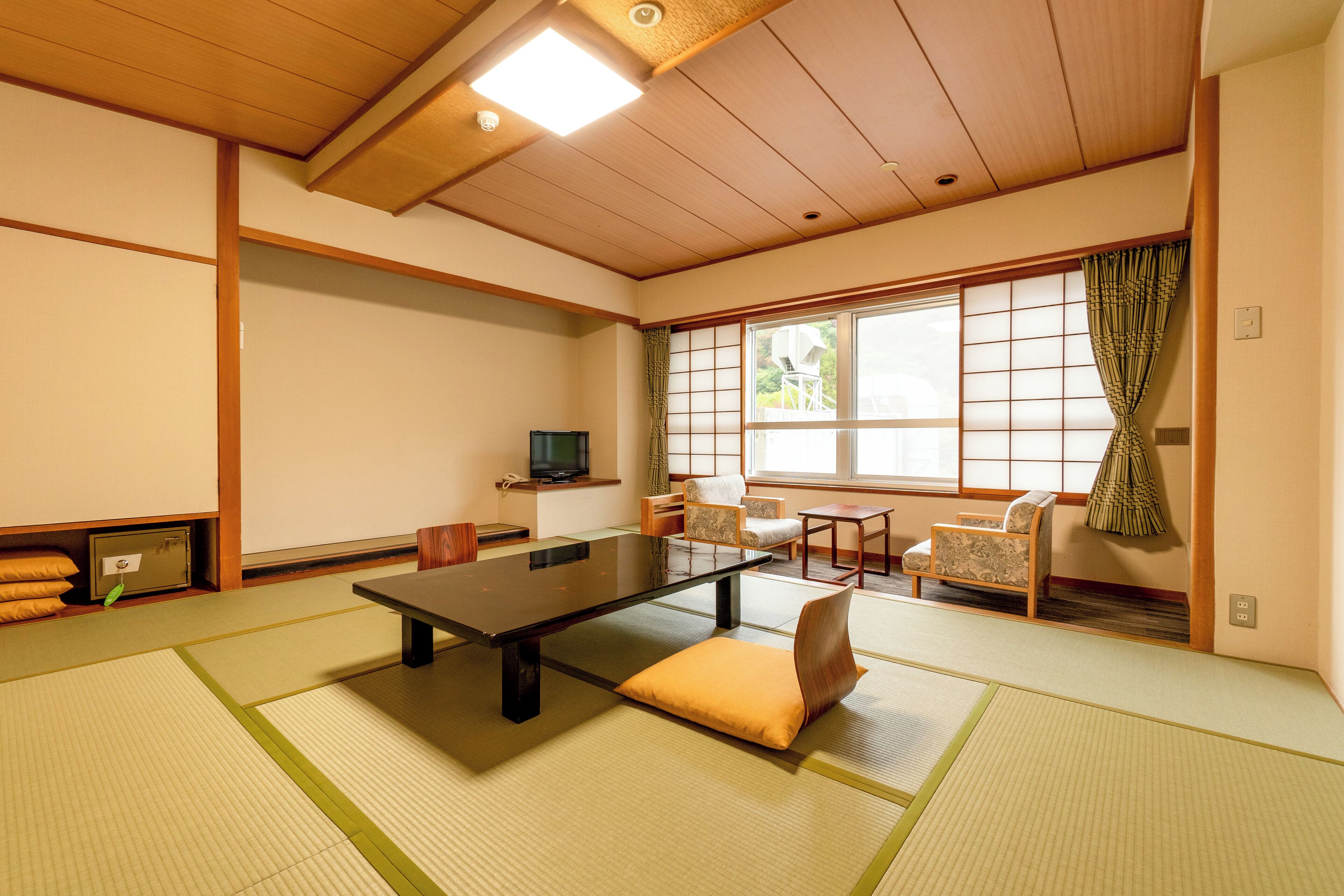 Une pièce de style japonais traditionnel, avec un sol recouvert de tatamis, une table basse et des paravents en papier de riz (shoji).