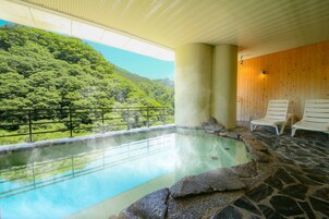 A hot spring with a view of a forested hillside.