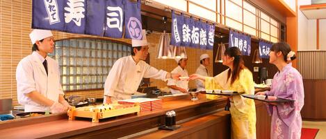 A traditional Japanese restaurant with a wooden counter and blue banners with Japanese characters.