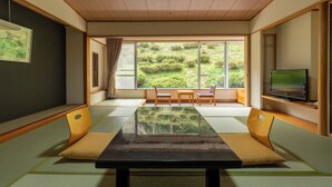 Une pièce de style japonais traditionnel, avec un sol recouvert de tatamis, une table basse et un téléviseur posé sur une étagère.