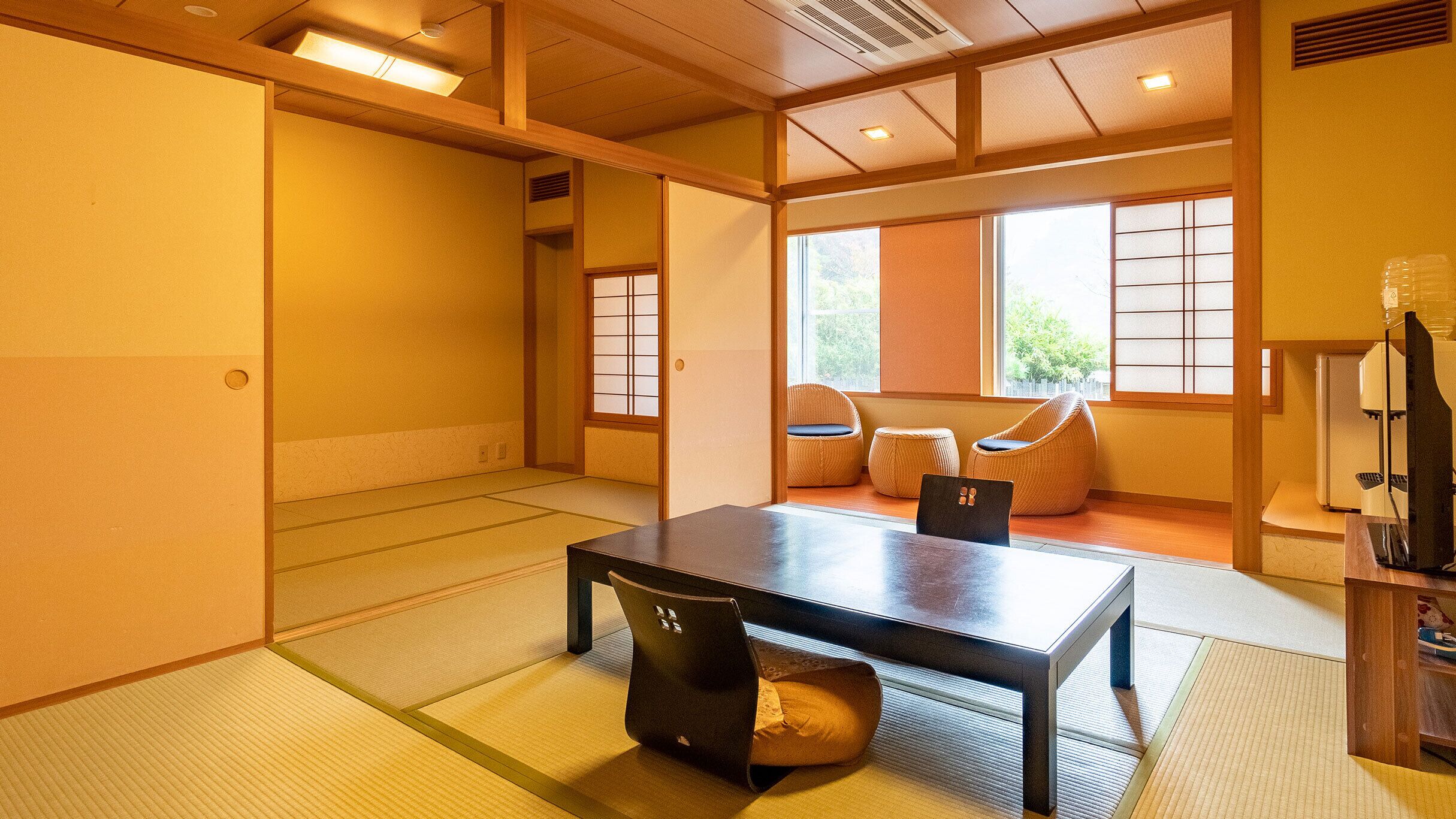 A traditional Japanese room with tatami flooring, a low table, and a sliding door.