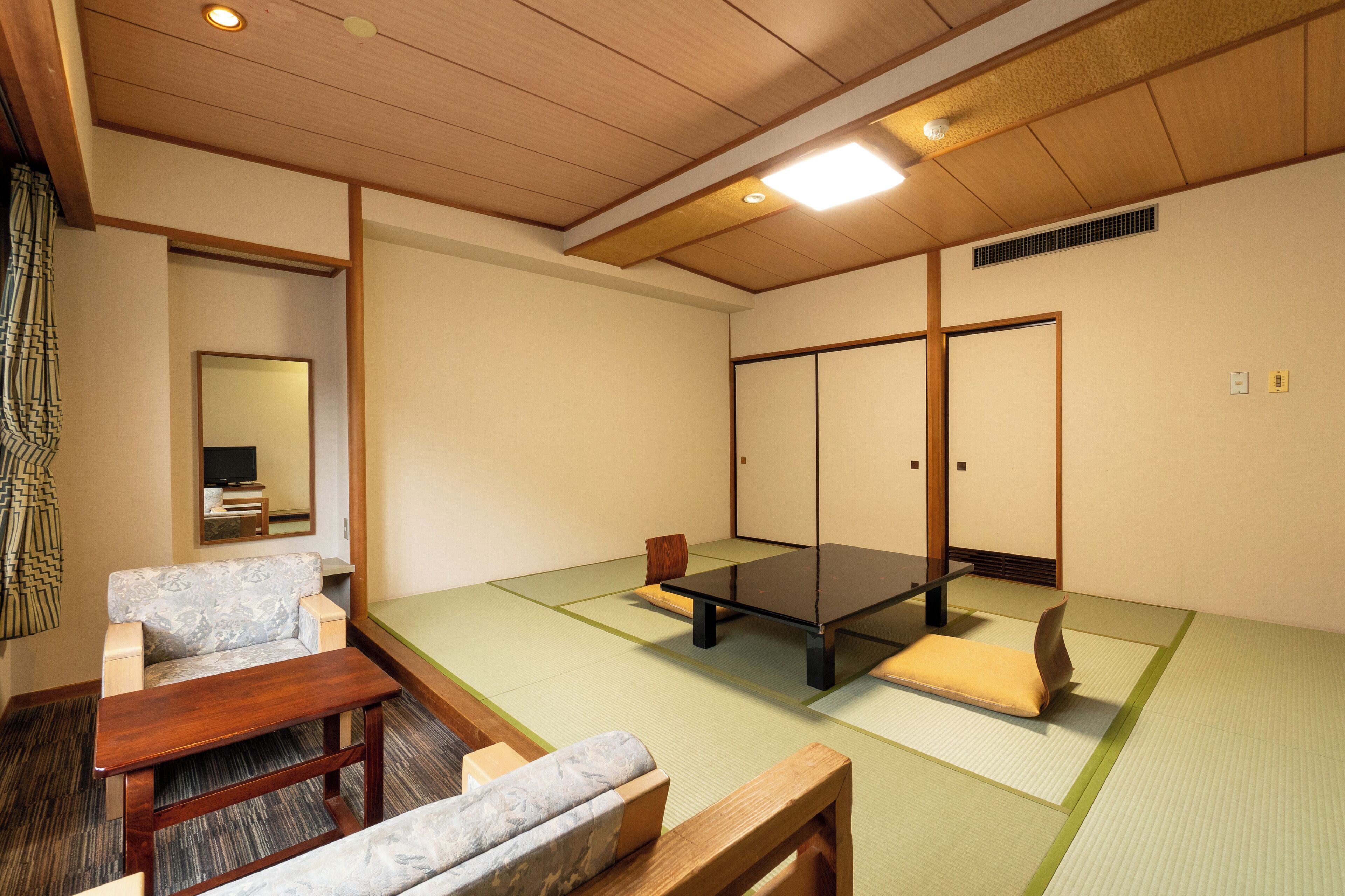 Um quarto japonês tradicional com esteiras de tatame, uma mesa de madeira baixa, um banco acolchoado e chão de tatame.