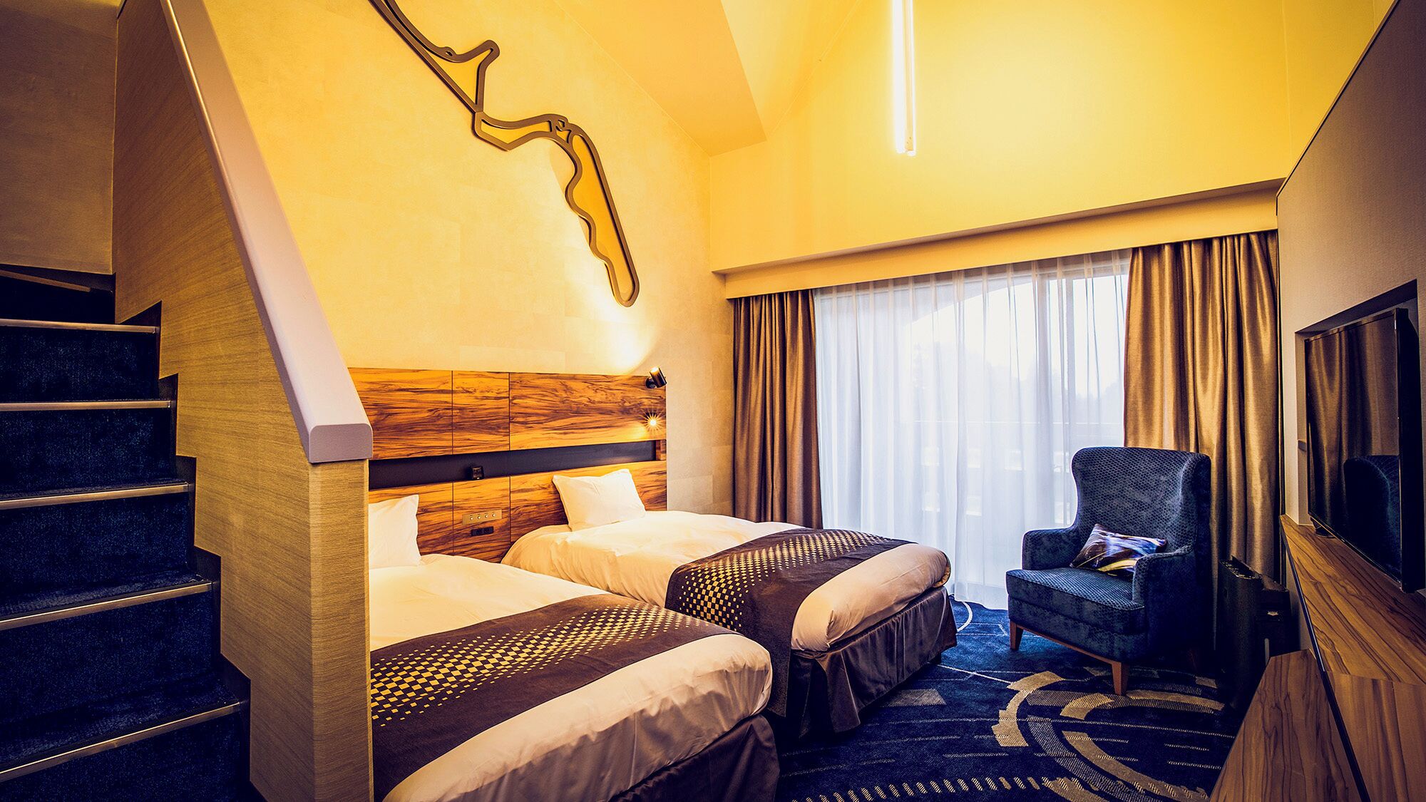 Habitación de hotel con dos camas, una silla, un televisor y una escalera.