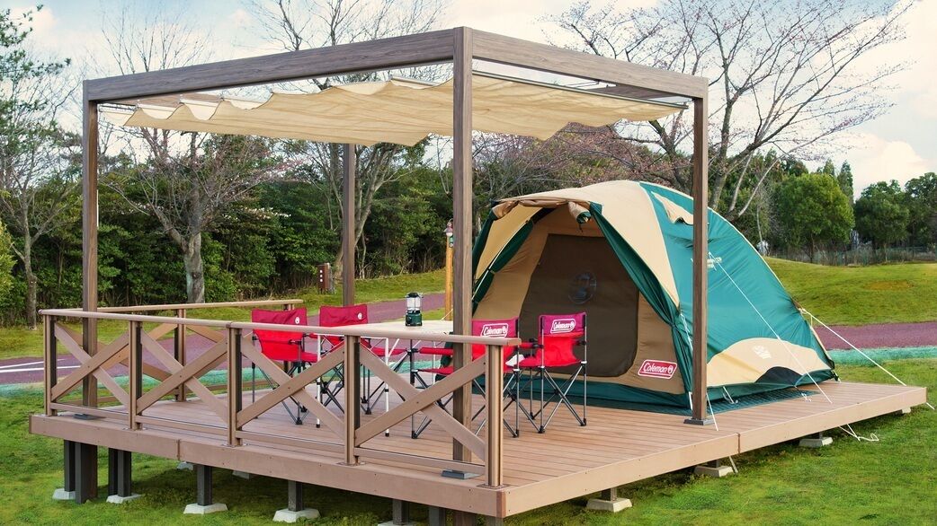 Un campamento montado con una tienda de campaña, una mesa y sillas sobre una terraza de madera.