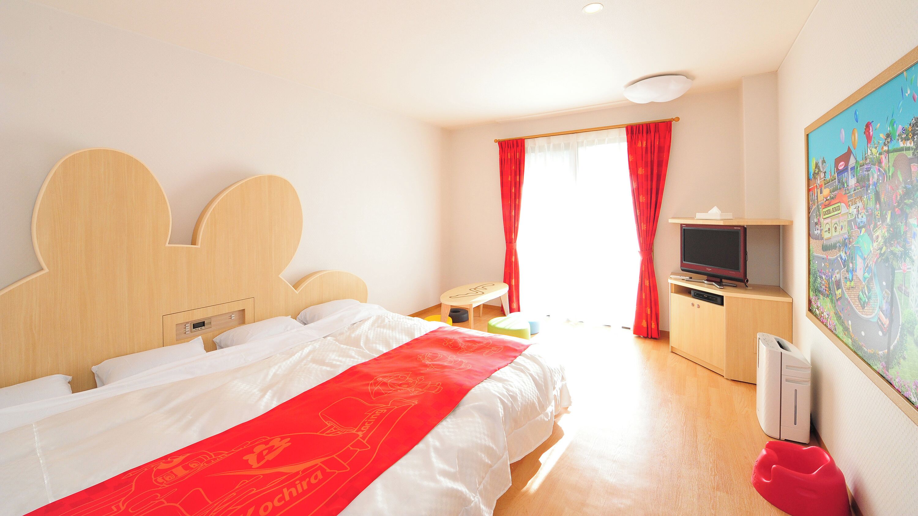 Una habitación de hotel con cama, televisión, escritorio y un cuadro en la pared.