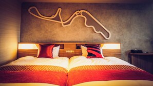 A hotel room with a bed, a headboard, a wall-mounted artwork, and a bedside table. - Suzuka Circuit Hotel (Suzuka)