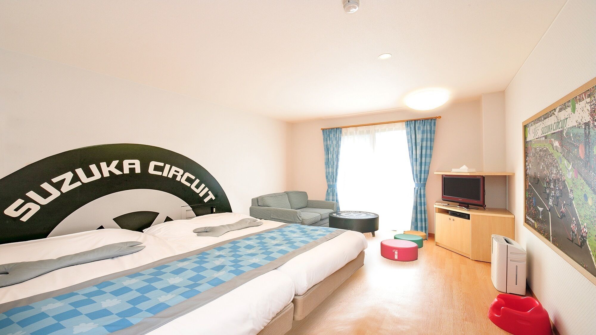 Habitación de hotel con cama, sofá, televisor, escritorio y un cuadro en la pared.