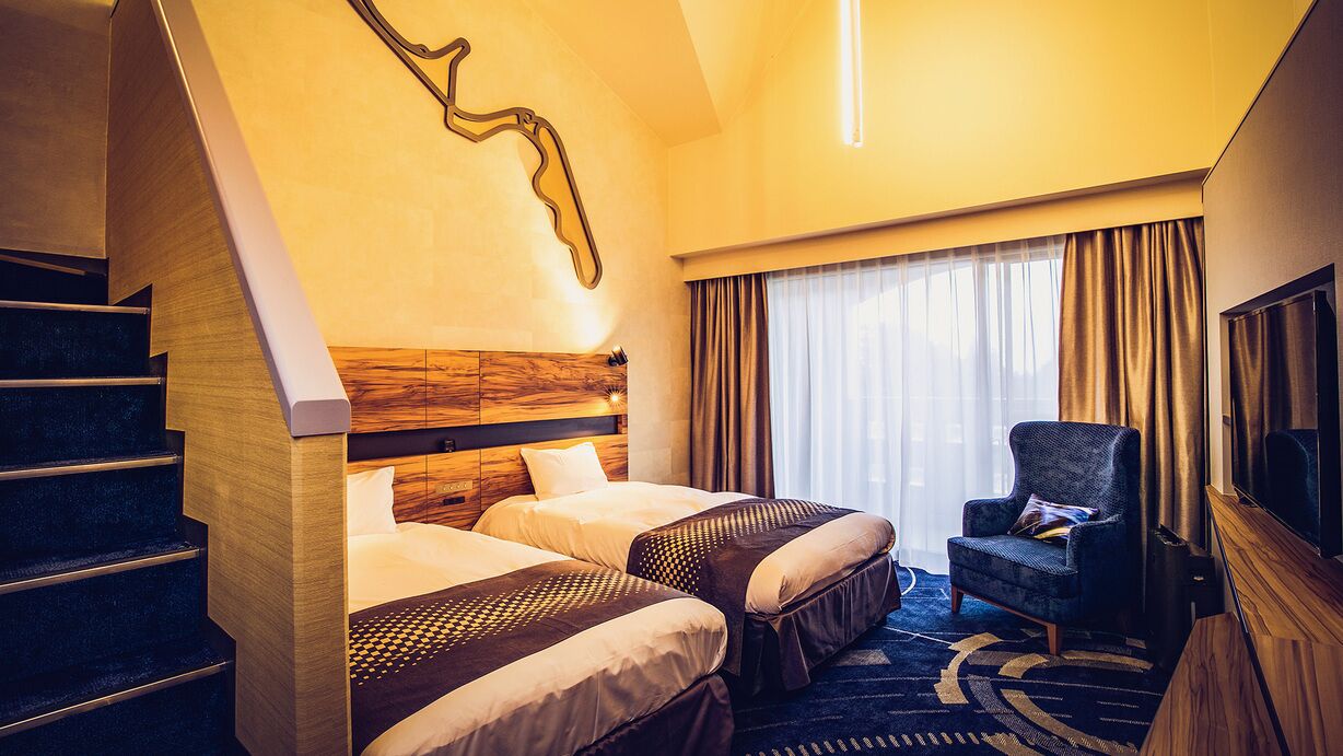 Una habitación de hotel con una escalera, dos camas, un televisor y una silla.