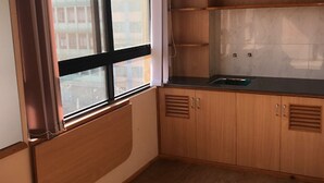 Une cuisine avec des meubles de rangement en bois, un plan de travail et une fenêtre avec des stores.