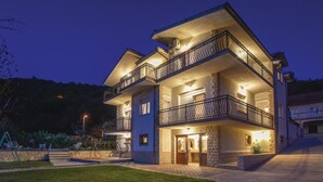 A multi-story house with a stone facade, multiple balconies, and a well-lit entrance. - Gorgeous home in Grab (Grab)