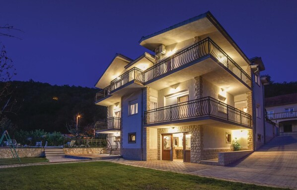 A multi-story house with a stone facade, multiple balconies, and a well-lit entrance. - Gorgeous home in Grab (Grab)