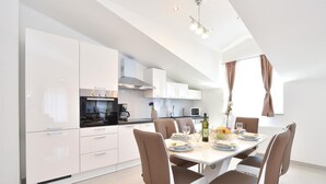 A modern kitchen with white cabinetry, a Bosch oven, and a dining area with a white table set for four. - Gorgeous home in Grab (Grab)