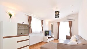 A modern living room with a sofa, TV, and a glass cabinet. - Gorgeous home in Grab (Grab)
