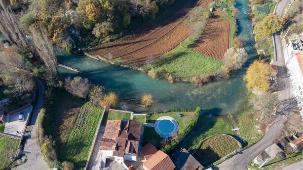 An aerial view of a residential area with a river, terraced fields, and a swimming pool. - Gorgeous home in Grab (Grab)
