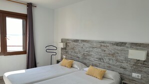 Un letto matrimoniale con biancheria da letto bianca e due cuscini, una testiera in legno, lampade da comodino e una finestra con tende.