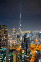 A nighttime cityscape with prominent skyscrapers, including a tall, illuminated tower, and a busy highway.