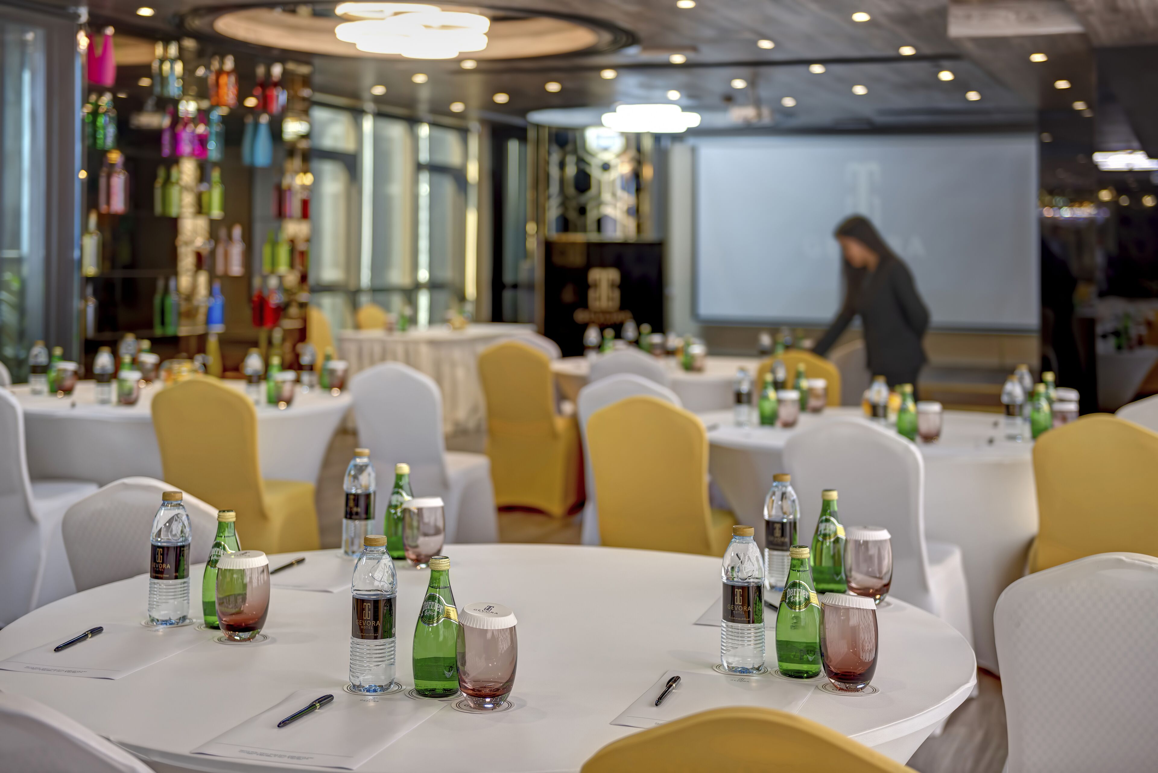 A conference room with round tables, chairs, and various beverages.