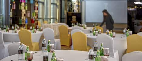 A conference room with round tables, chairs, and various beverages.