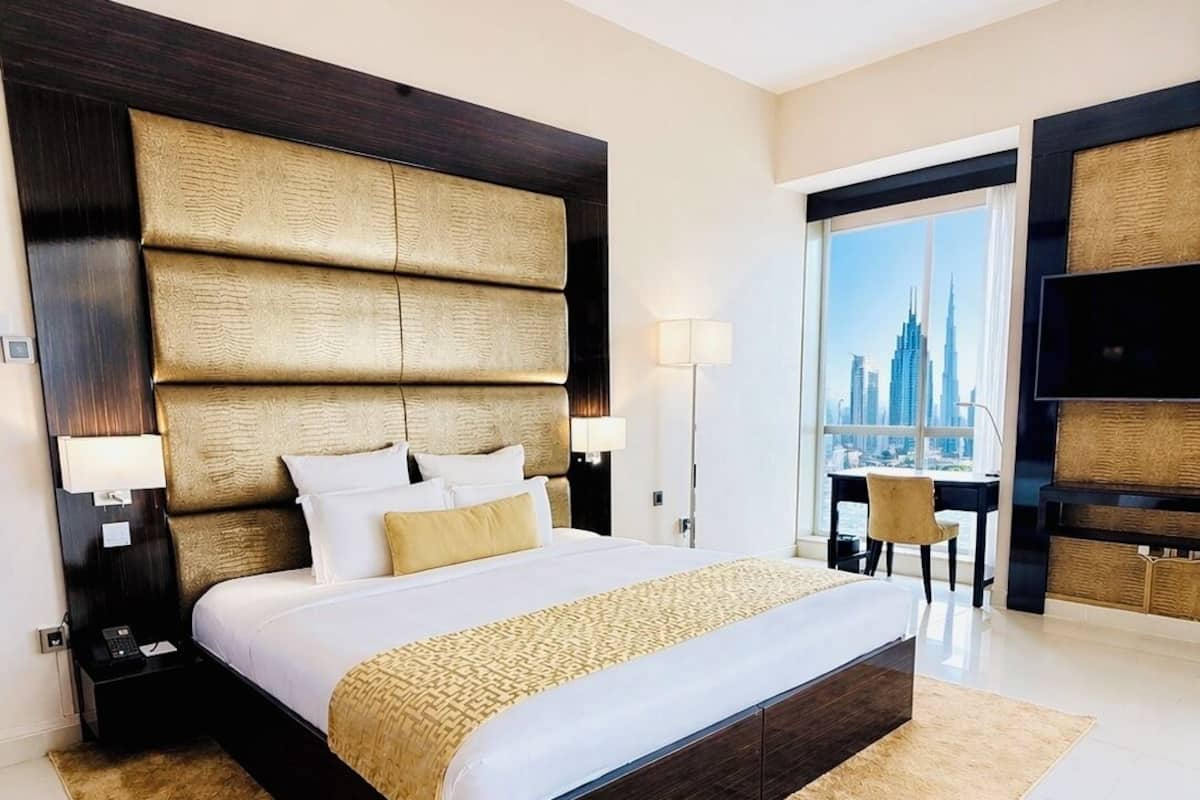 Une chambre d’hôtel moderne, dotée d’un grand lit, d’un bureau et offrant une vue sur le paysage urbain.