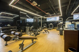 Un gimnasio con diversos equipos de ejercicio, como mancuernas, bancos y máquinas de pesas.