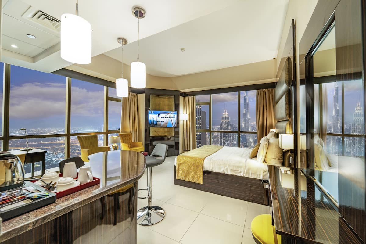 Une chambre d’hôtel moderne dotée d’un grand lit, d’un bureau avec une chaise, d’une télévision et offrant une vue sur la ville.