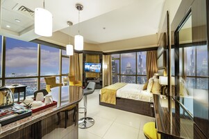 A modern hotel room with a large bed, a desk with a chair, a TV, and a city view.