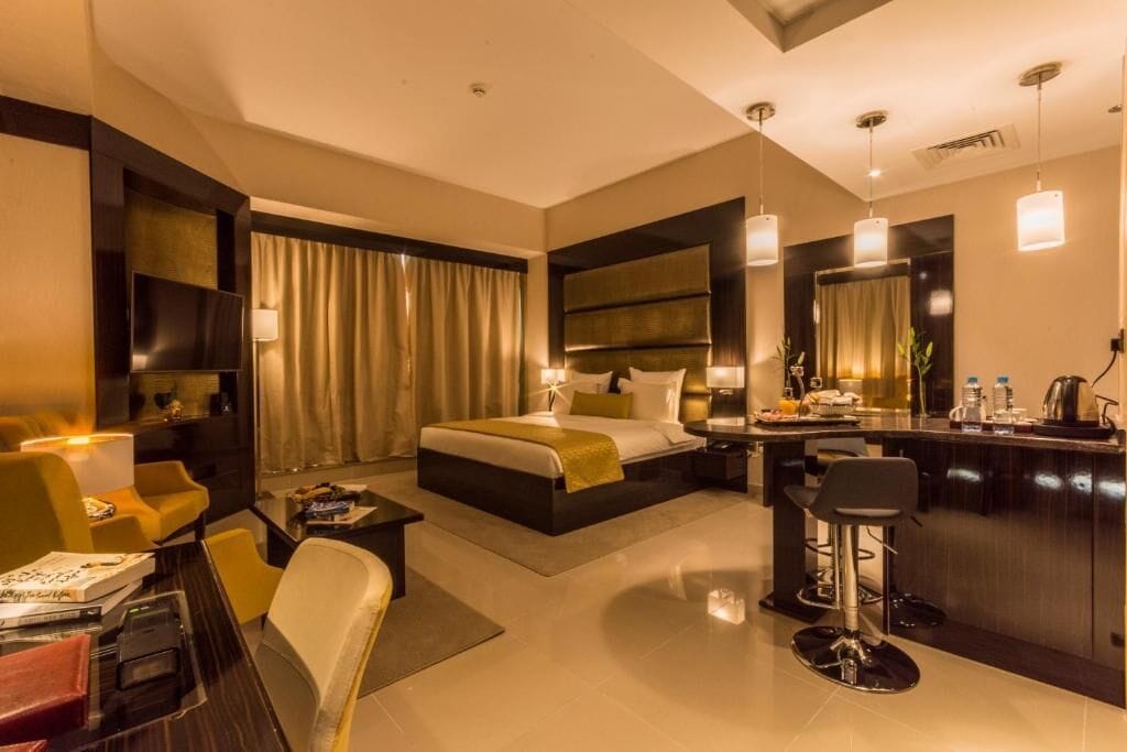 Une chambre d’hôtel moderne dotée d’un grand lit, d’un bureau, d’un coin bar et d’un espace salon.