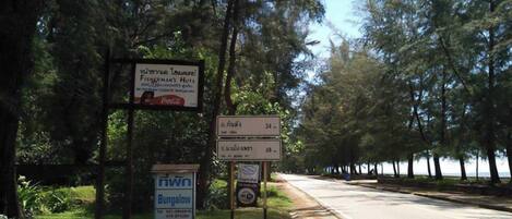 Un cartel al borde de la carretera con varios anuncios, incluyendo uno de cabañas y otro de Cabañas Fisherman's Huts.