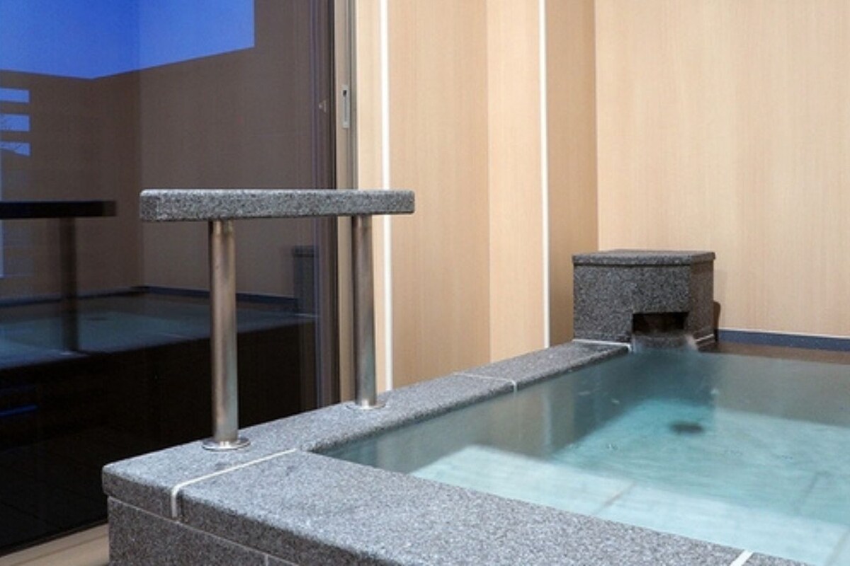 A spa area with a stone bench and a small stone structure, possibly a sauna or hot tub, in a room with wooden paneling.