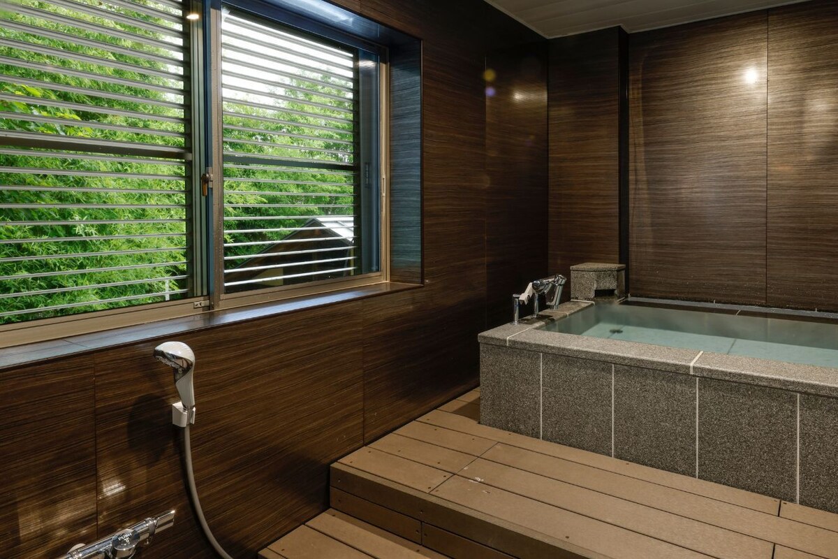 A modern bathroom with a built-in hot tub, a window with blinds, and a shower area.