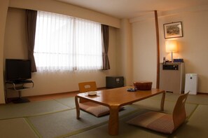 A hotel room with a wooden table, two chairs, a television, a desk lamp, a small cabinet, and a picture on the wall. - Hotel Luna Park (Matsuyama)