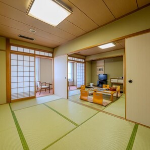 A traditional Japanese room with tatami flooring, a low table with cushions, and sliding doors. - Hotel Luna Park (Matsuyama)