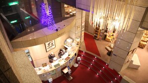 Un hall d’hôtel avec un comptoir d’accueil, un sapin de Noël et un escalier.