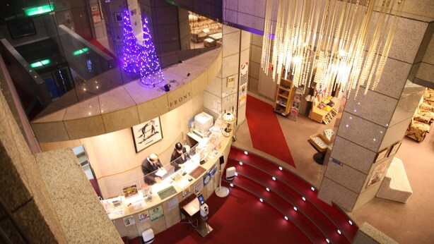 A hotel lobby with a reception desk, a Christmas tree, and a staircase. - Hotel Luna Park (Matsuyama)