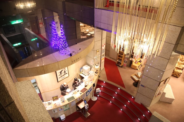 A hotel lobby with a reception desk, a Christmas tree, and a staircase. - Hotel Luna Park (Matsuyama)