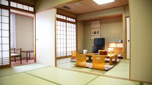 Une pièce de style japonais traditionnel, avec un sol recouvert de tatamis, une table basse avec des coussins et des portes coulissantes.