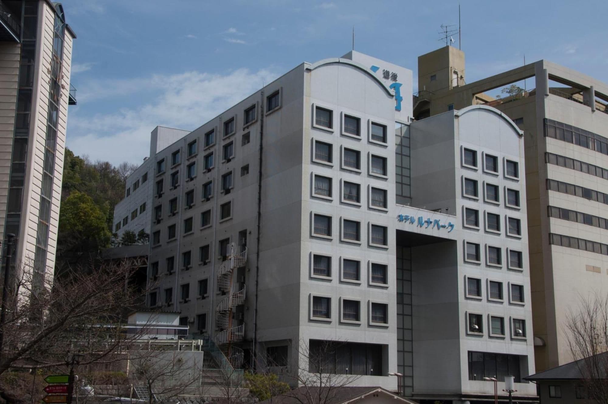 A multi-story building with a modern architectural design, featuring a prominent entrance with a curved overhang and a sign in a foreign language.