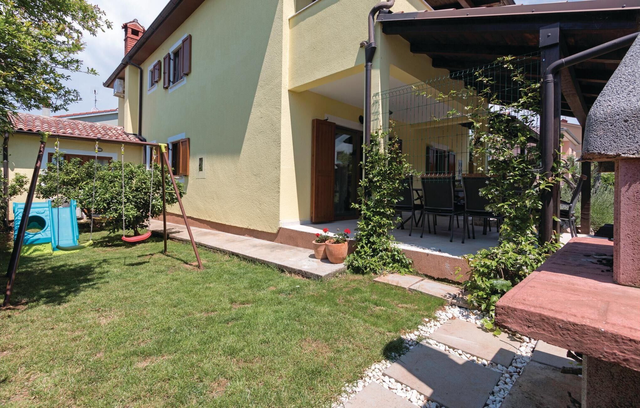A residential property with a covered patio, a swing set, and a small garden area.