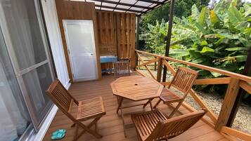 Relax on the deck with a view of lush green surroundings, featuring a round table and comfortable seating for four.
