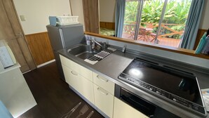 A compact kitchen with a built-in stove, sink, and dishwasher. - Bise House (Motobu)