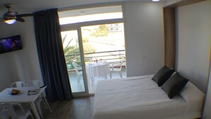 Een hotelkamer met een bed, een tafel met stoelen, een televisie en een balkon met een tafel en stoelen.