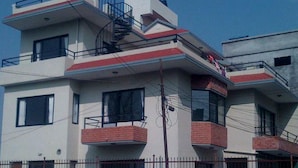 Un edificio de varios pisos con balcones, una escalera y un área cercada al frente.
