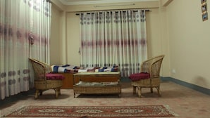 Una sala de estar con dos sillones de mimbre, un sofá pequeño y un tapete estampado.