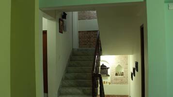 A staircase with a marble finish and wooden handrails, leading to a room with a brick wall and a small alcove with decorative items.