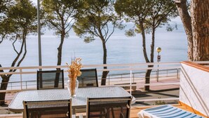 Eine Terrasse mit Tisch und Stühlen mit Blick auf ein Gewässer und Bäume.