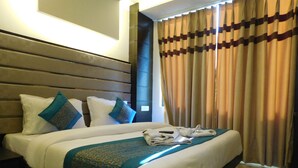 A hotel room with a large bed, two pillows, a blanket, and a remote control. - Hotel Gauranga Nearest New Delhi Railway Station (New Delhi)
