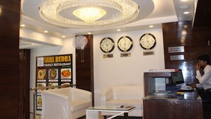 A restaurant interior with a chandelier, clocks, and a counter. - Hotel Gauranga Nearest New Delhi Railway Station (New Delhi)