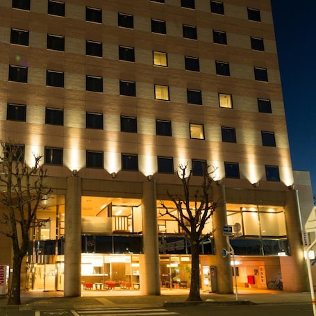A multi-story hotel with a modern design, featuring a central atrium with seating and a staircase.