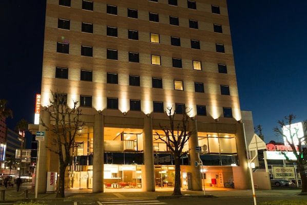 A multi-story hotel with a modern facade, illuminated windows, and a visible entrance with a sign.